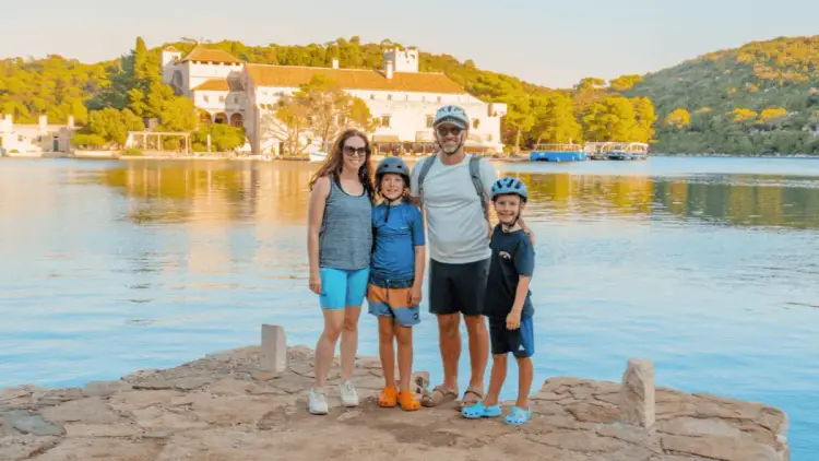 Family pose for a photo in Mljet National Park while on a premium family catamaran cruise together during summer holidays.