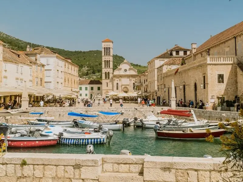 Boats moored in the harbour of Hvar Town, Croatia, surrounded by historic stone buildings and waterfront cafés — a top destination for luxury sailing holidays and catamaran cruises with Yacht Getaways.