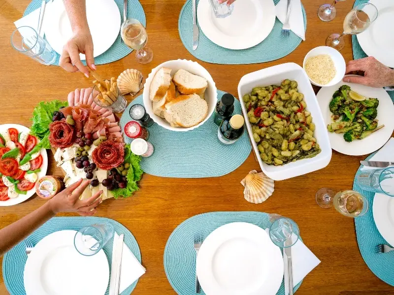 Vibrant dishes of food on a table with hands reaching in, a standard inclusion meal on Yacht Getaways catamaran cruises.