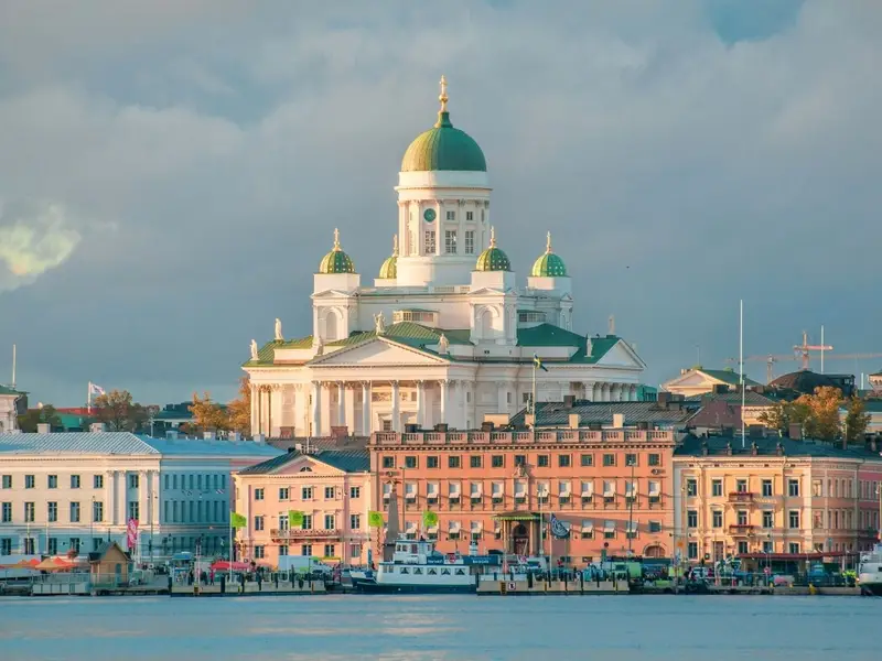 Helsinki Cathedral rises above the South Harbour waterfront in Helsinki, Finland, with its white neoclassical façade and distinctive green domes under a dramatic sky. A calm, walkable Nordic capital scene that suits an article on the safest places to visit in Europe, reflecting Finland’s strong reputation for stability, reliable public transport, and easy, low-stress city breaks for mature travellers.