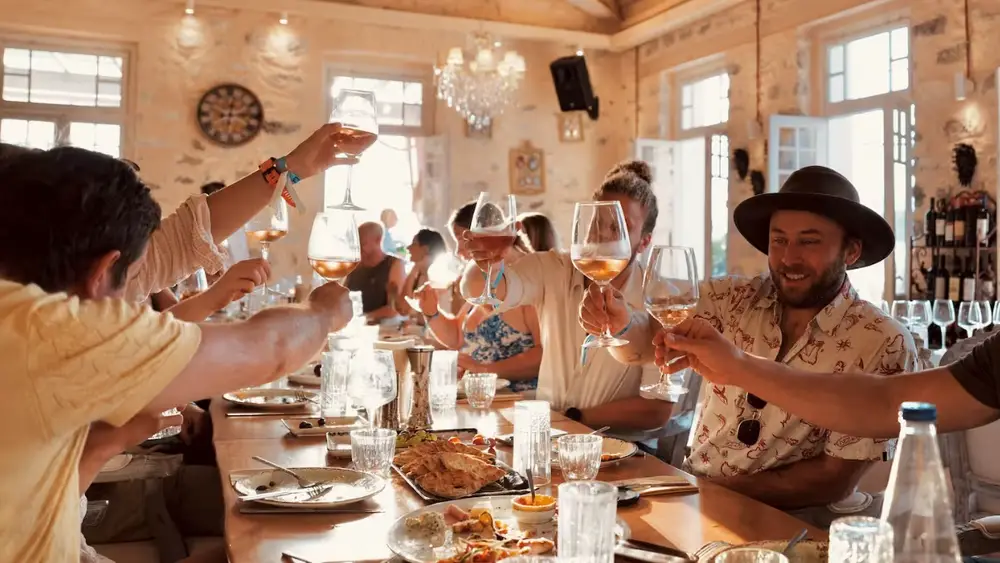 Guests enjoying a Greek wine tasting and local dining experience during a luxury yacht holiday through the Saronic Gulf islands from Athens.
