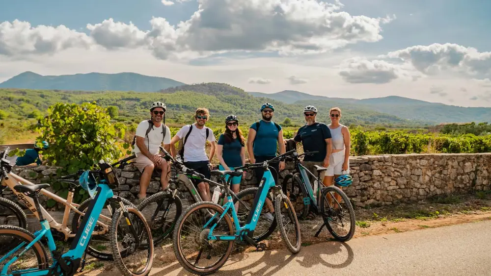 Group of guests on a luxury cycling cruise in Croatia with Yacht Getaways cycling around Hvar island with vineyards behind them.