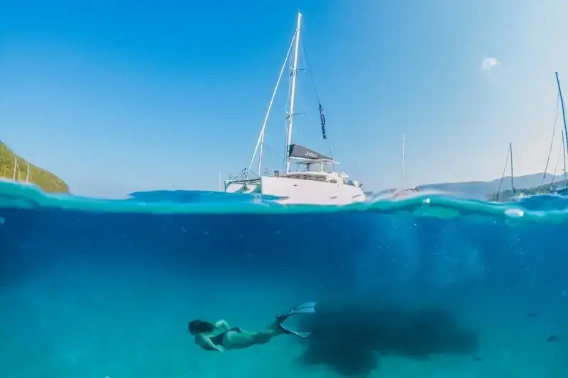 A woman snorkelling in crystal clear Mediterranean waters while on a luxury catamaran cruise with Yacht Getaways.