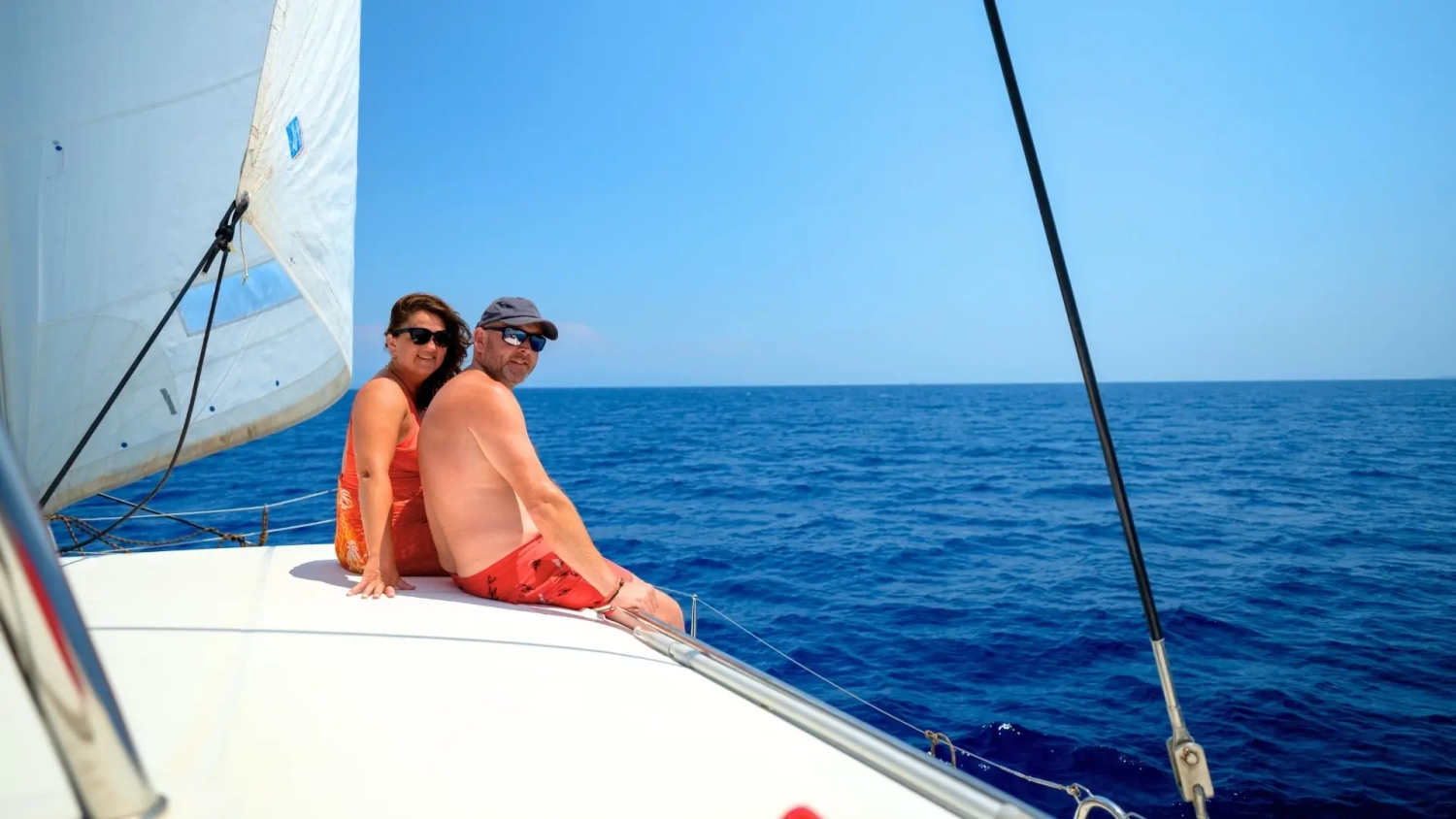A couple relaxing on the deck of a sailing yacht with open blue sea around them, representing the restorative appeal of blue health travel and holidays at sea. The image captures the calm, spacious feeling of a luxury yacht holiday in the Mediterranean, where time on the water, fresh air and slow sailing through Greece or Croatia can support a more relaxed and wellness-focused escape.