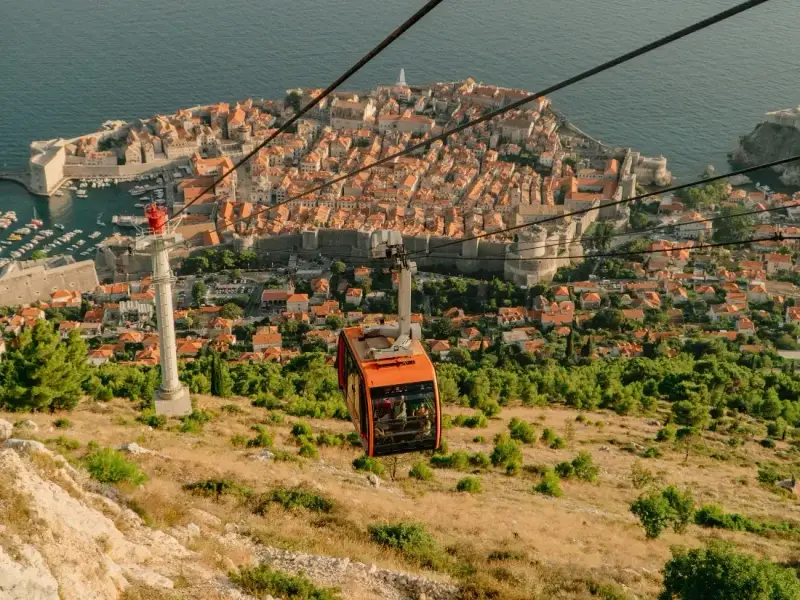 Dubrovnik cable car descending Mount Srđ with sweeping views over Dubrovnik Old Town, its terracotta rooftops, fortified city walls and the Adriatic Sea in Croatia. This image highlights one of the best things to do in Dubrovnik, offering a panoramic perspective of the UNESCO-listed city and one of the most memorable viewpoints in any Dubrovnik travel guide.
