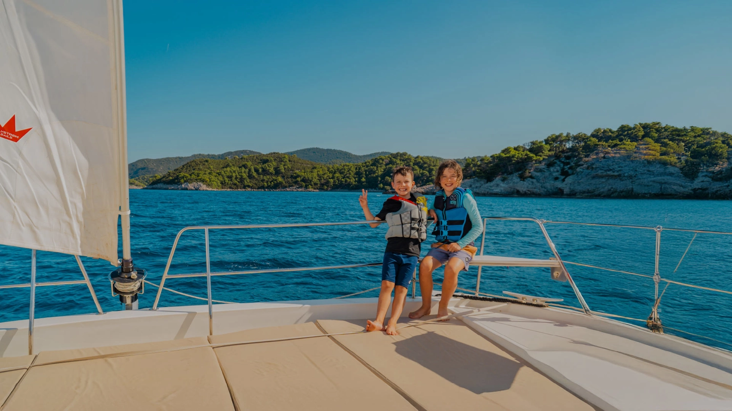 Family sailing holiday – Two kids on the bow of a catamaran in Croatia