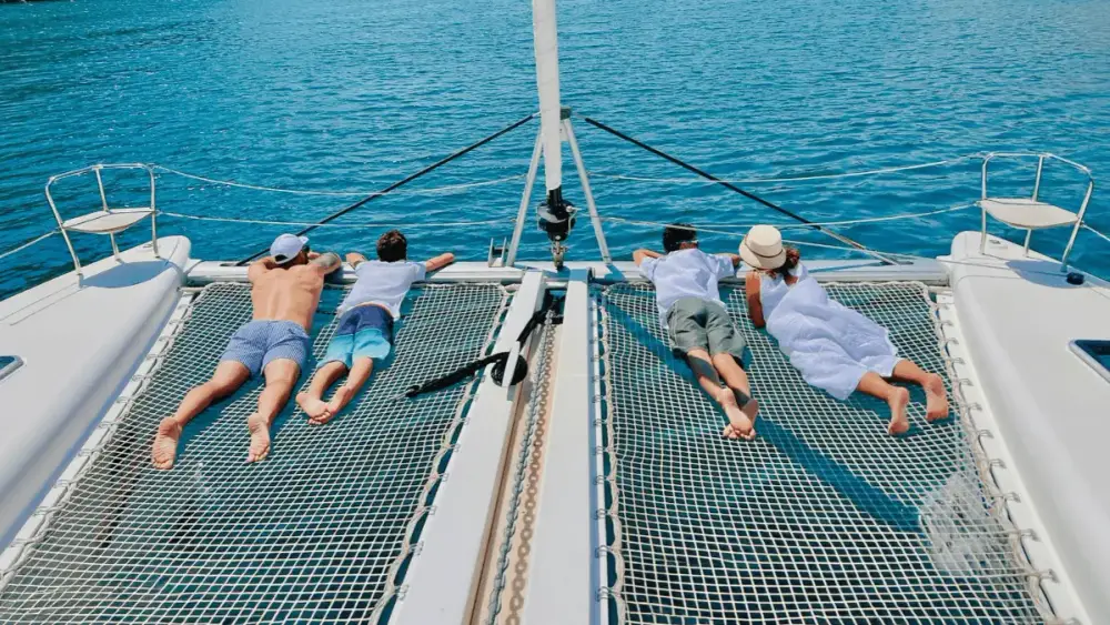 Family relaxing on the bow while on a kids-friendly cruise in Croatia by catamaran.