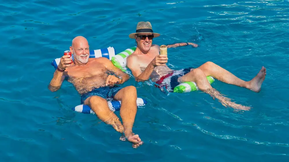 Two men on floaties drinking beers