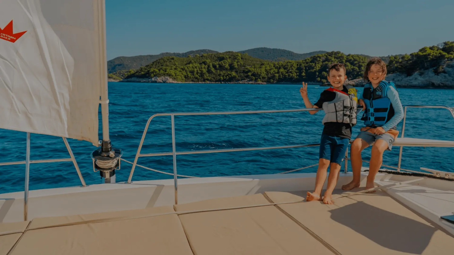 Family sailing holiday – Two kids on the bow of a catamaran in Croatia