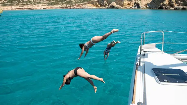 Group of women dive into the ocean from a catamaran