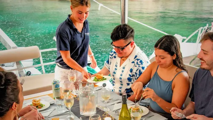 Group of friends enjoying a private catamaran charter in Greece, swimming and relaxing together with Yacht Getaways.