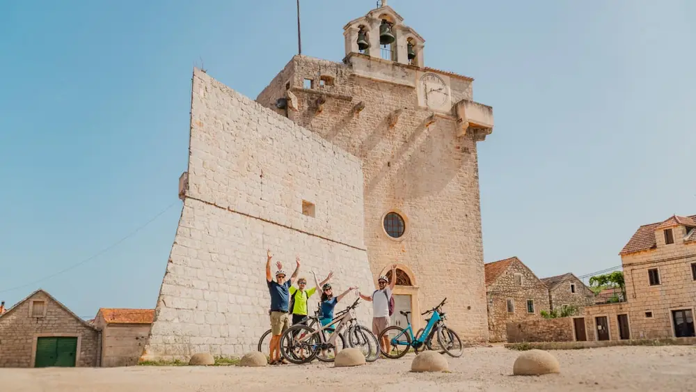 Vrboska on the island of Hvar with cyclist standing before a historic monastery during a luxury cycling cruise in Croatia.