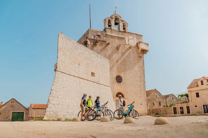 Photo of cycling cruise group in Croatia in front of a church in Vrboska, Hvar.