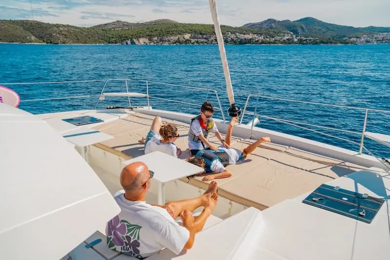 Happy family relaxes and plays aboard a luxury catamaran cruise in the Mediterranean.