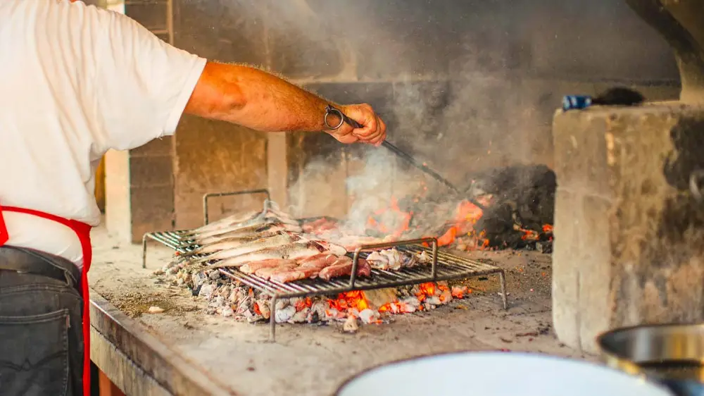 Man cooking fish on an outdoor grill