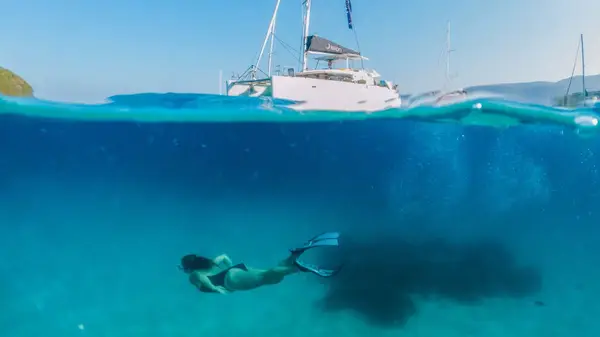 Woman snorkelling under a catamaran