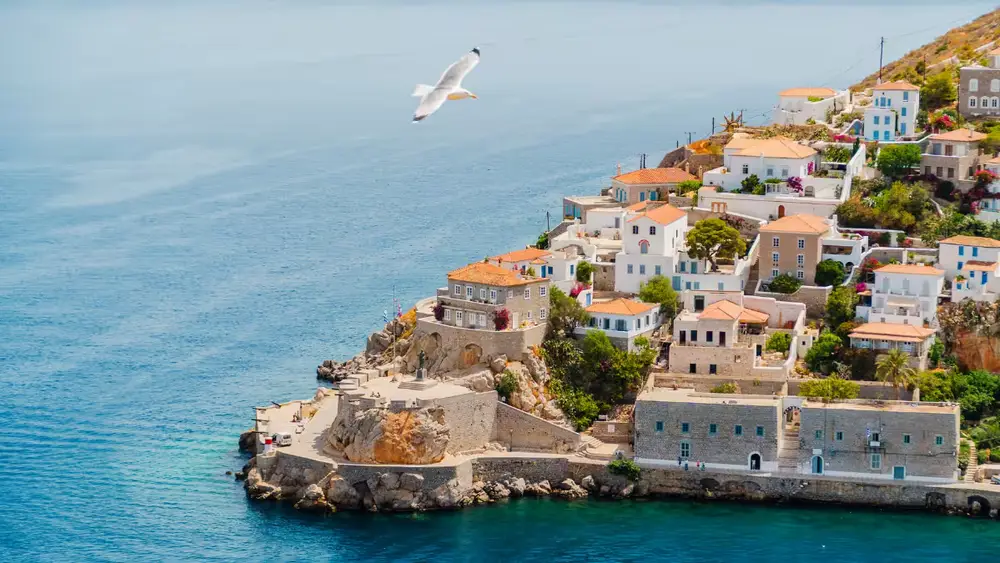 Traditional stone houses overlooking the blue Aegean Sea on Hydra, one of the beautiful Greek islands visited on an Athens sailing holiday through the Saronic Gulf.