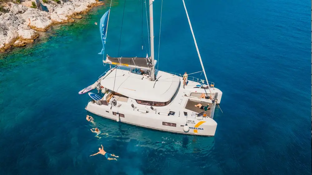 Group of people swimming next to a catamaran