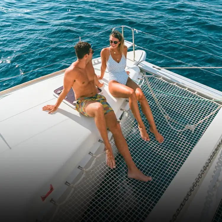 Couple relaxing on the bow of a Yacht Getaways catamaran, enjoying the flexible pace of a Greece and Croatia sailing holiday.