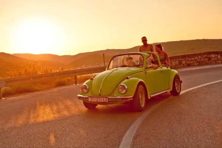 Friends drive car at sunset in Ios