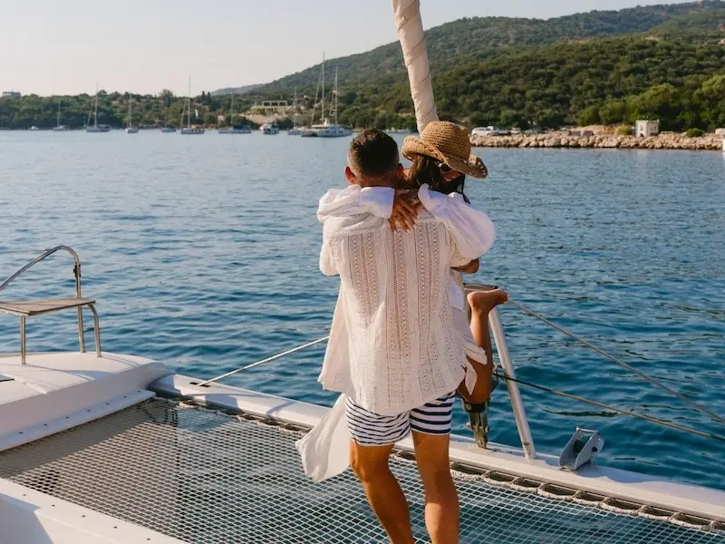 A happy couple on a luxury catamaran cruise dancing on the bow while on vacation in the Mediterranean with yacht Getaways.