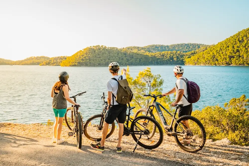 Photo of 3 people looking out over the turquoise lakes of Mljet National Park while on a cycle and sailing tour of Croatia.