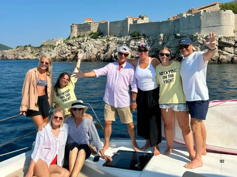 Yacht Getaways guests and crew together aboard a luxury catamaran off the historic city walls of Dubrovnik, Croatia, during a Mediterranean yacht cruise, capturing the small-group sailing experience behind Yacht Getaways’ Best Yacht Cruises nomination.