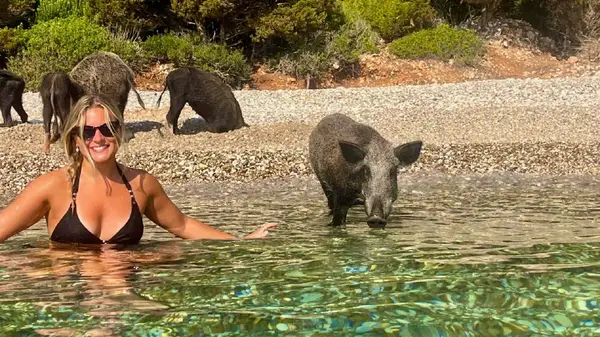 Woman swims with a pig at Atokos Bay