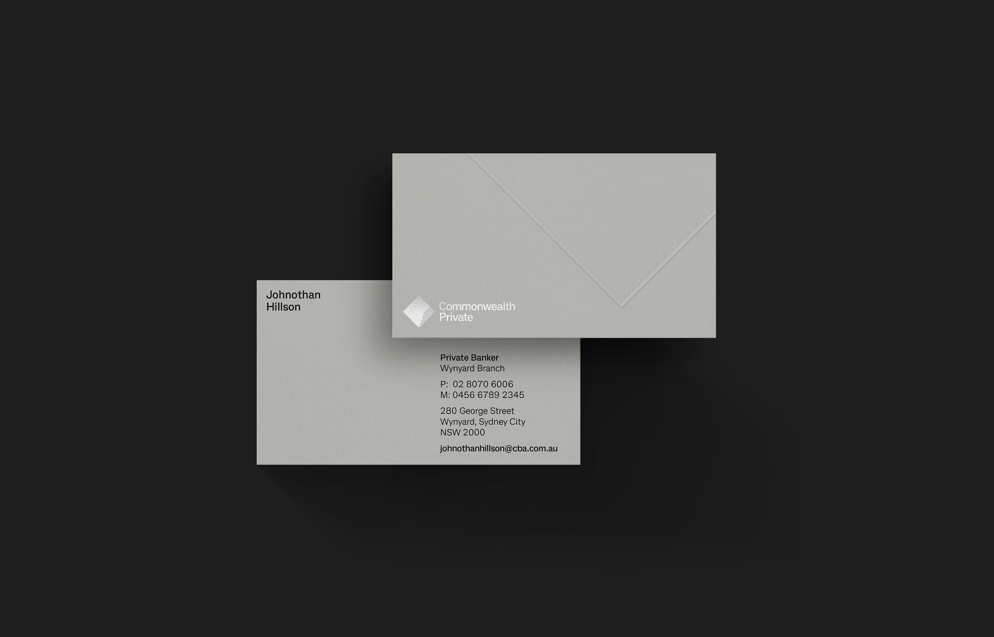 Grey business card and envelope carrying the Commonwealth Private diamond, shot on black