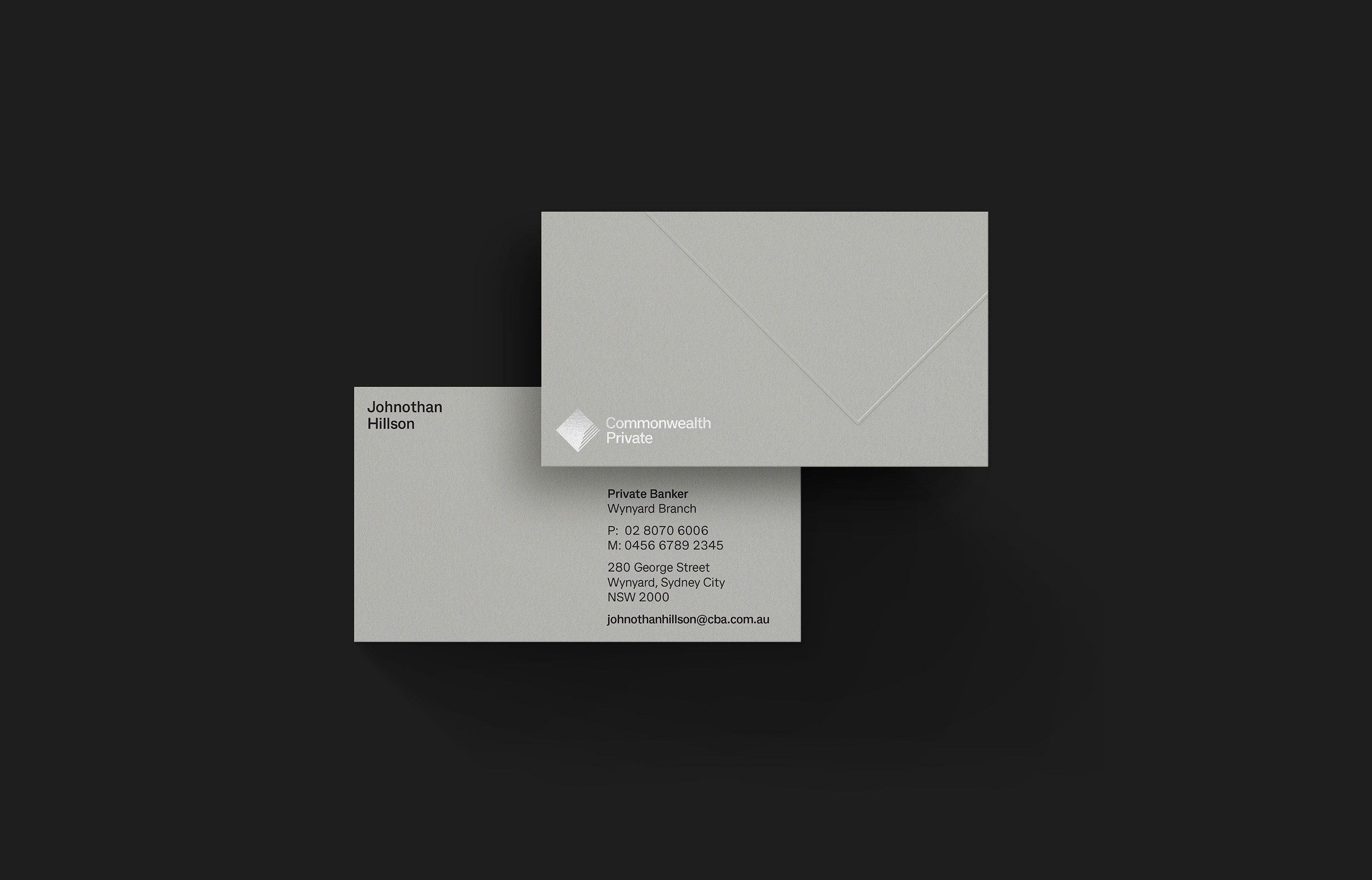 Grey business card and envelope carrying the Commonwealth Private diamond, shot on black
