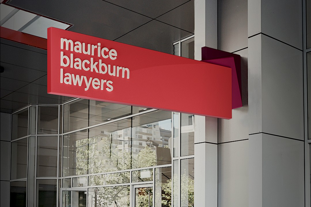 Projecting red blade sign reading 'maurice blackburn lawyers' above a glazed office entrance