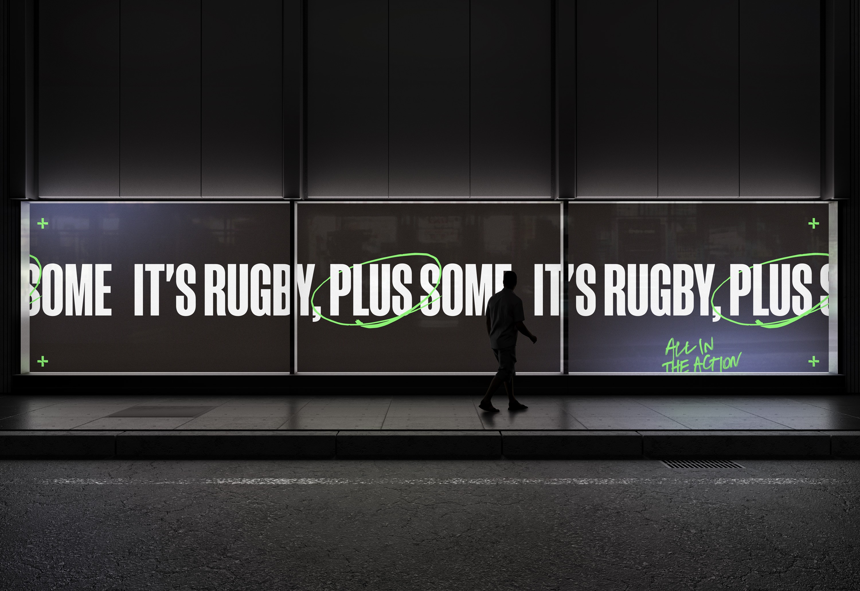 Backlit street billboards reading 'It's rugby, plus some' with a looping green scrawl at night