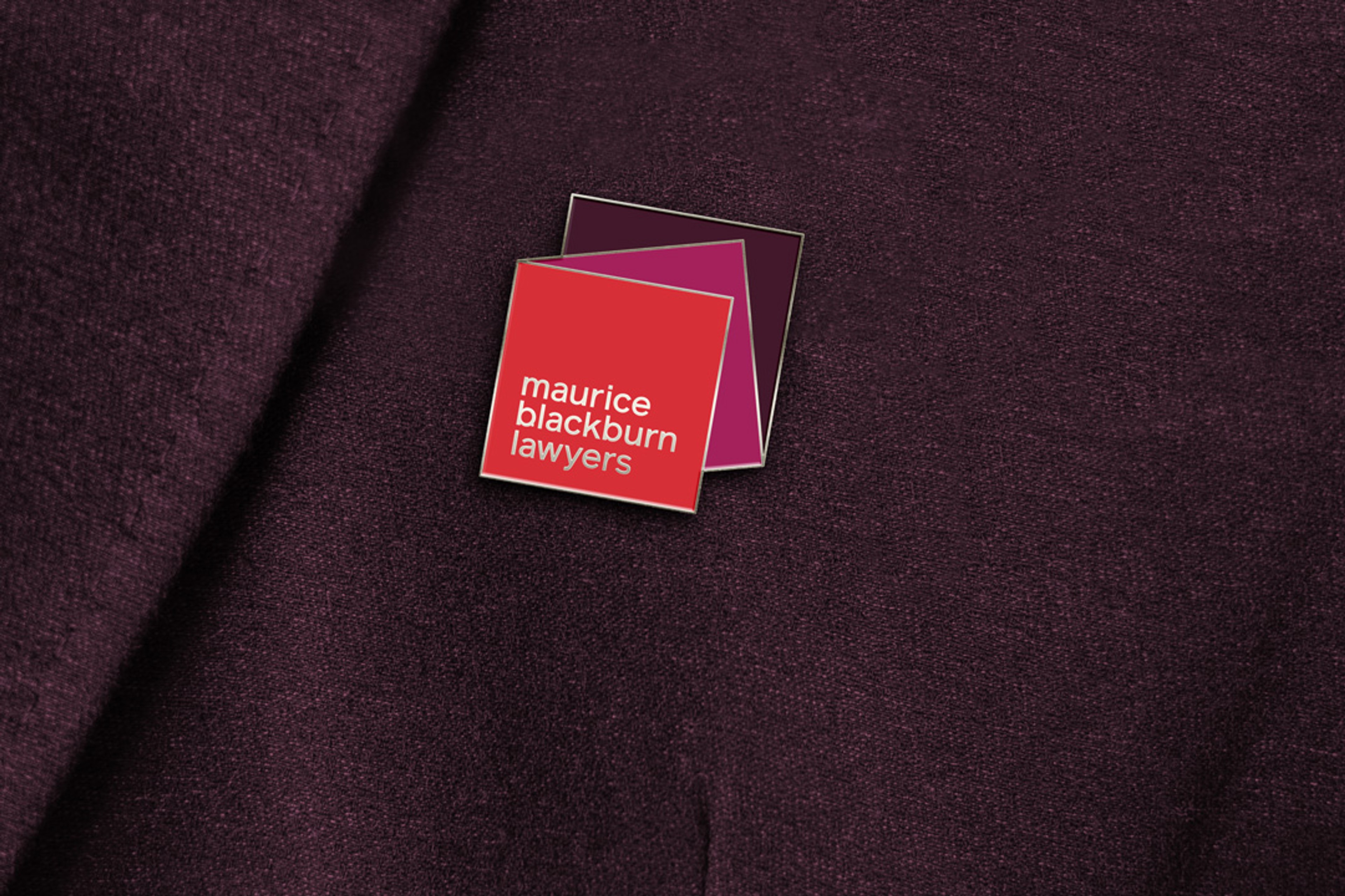 Enamel lapel pin of the layered square logo, pinned to plum wool fabric
