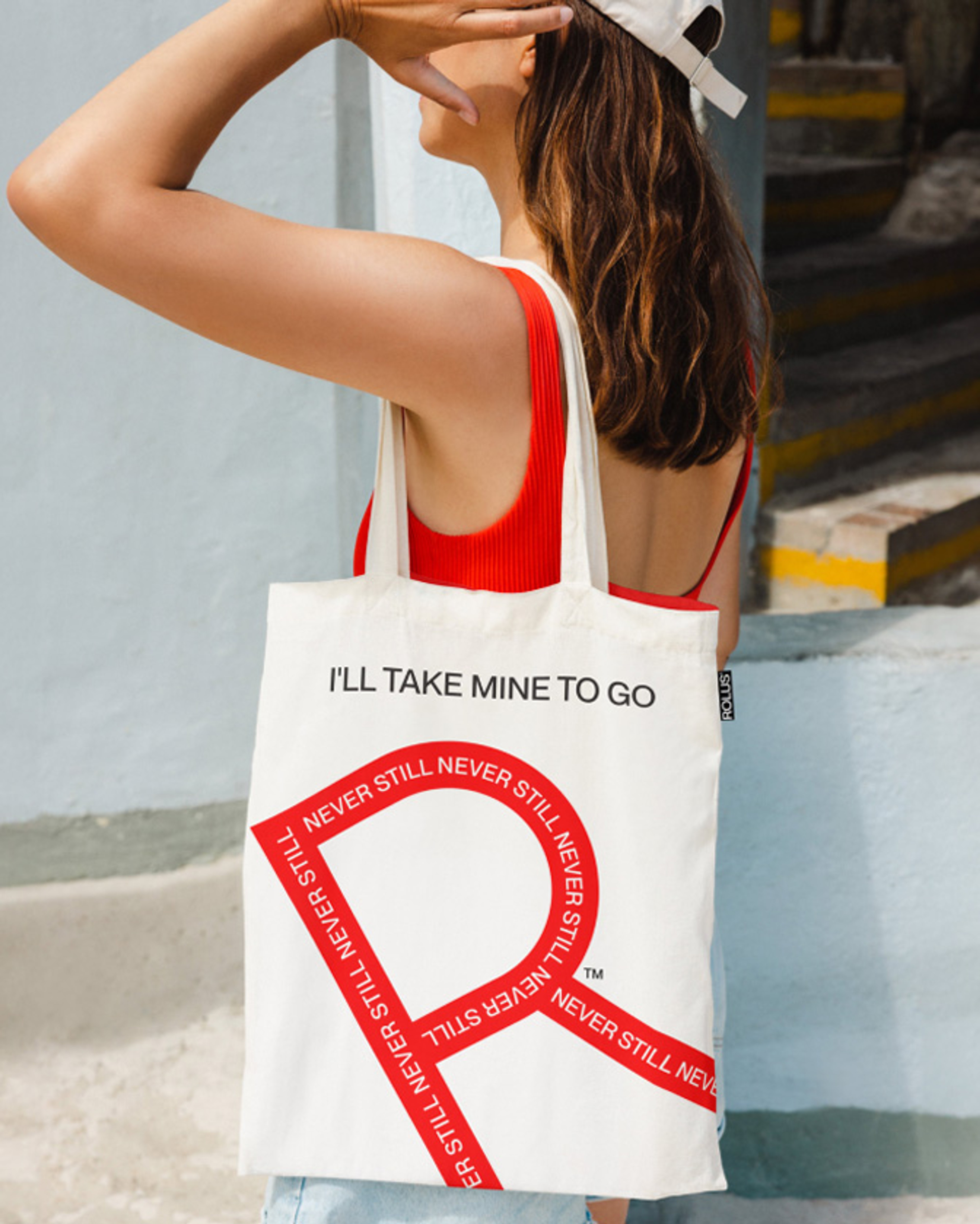 Canvas tote printed 'I'll take mine to go' with a red R built from Never Still type