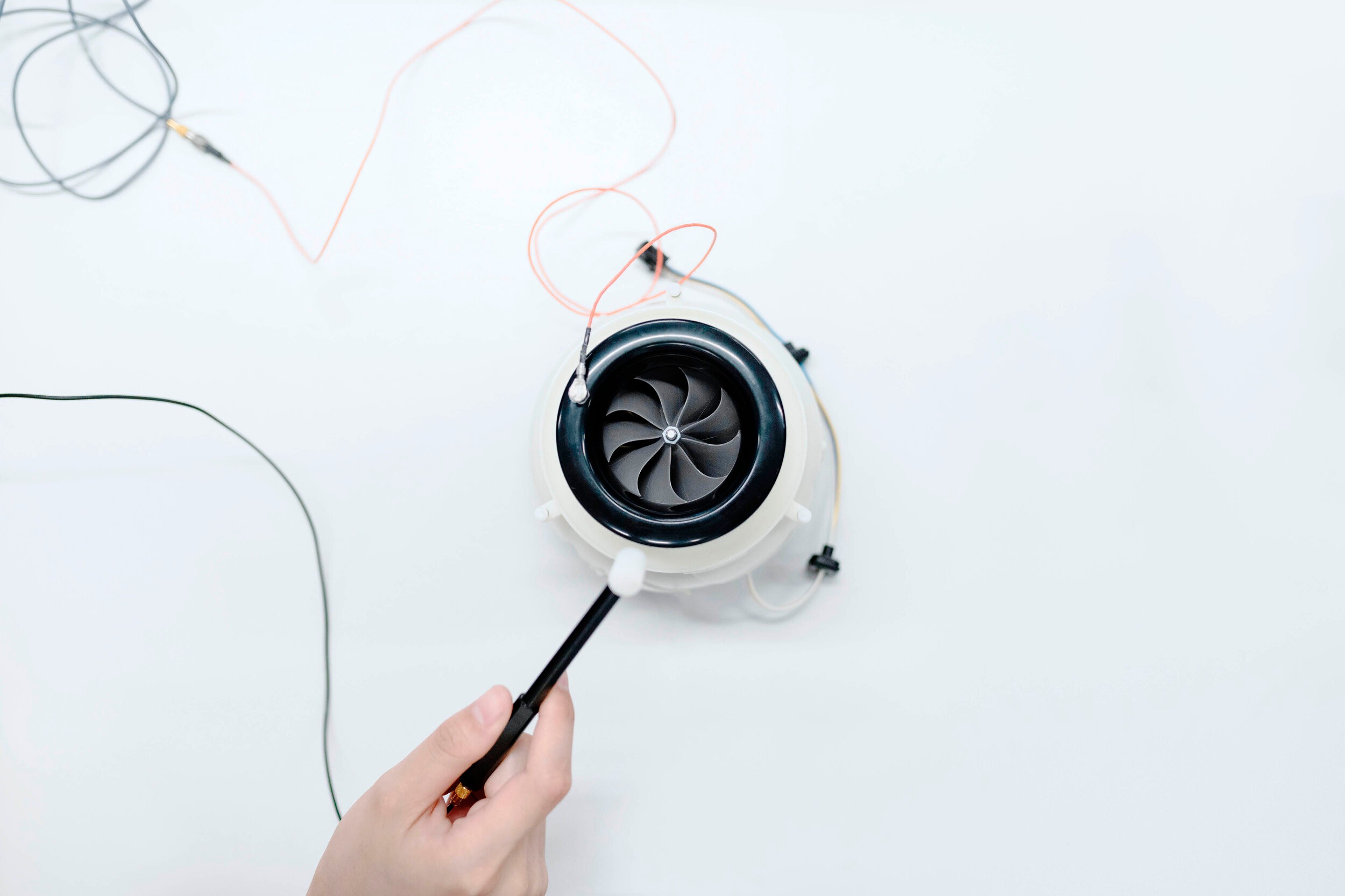 Hand probing a black turbine fan wired up on white, from the innovation photography set