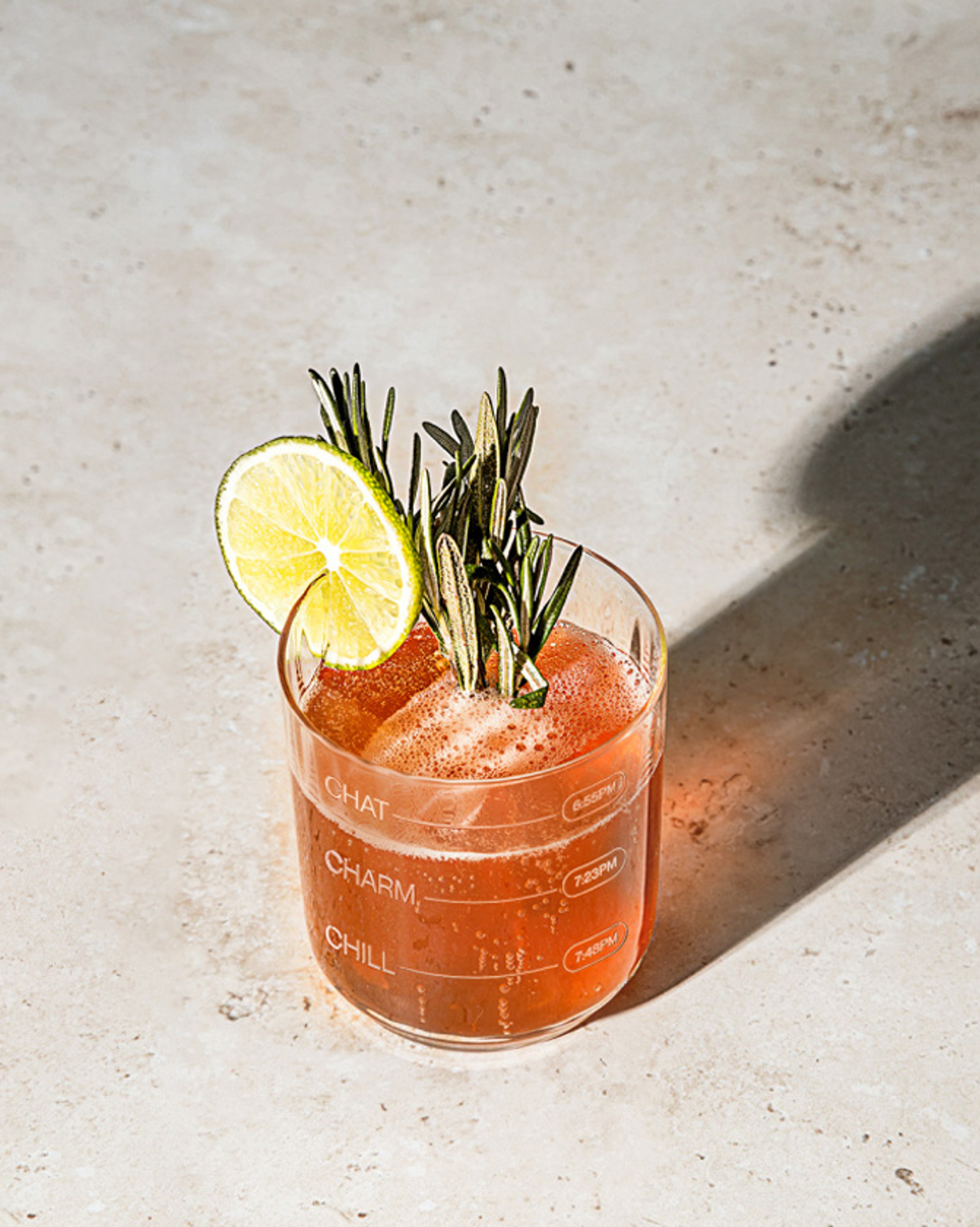 Branded tumbler etched with Chat, Charm and Chill time markers, holding a garnished spritz