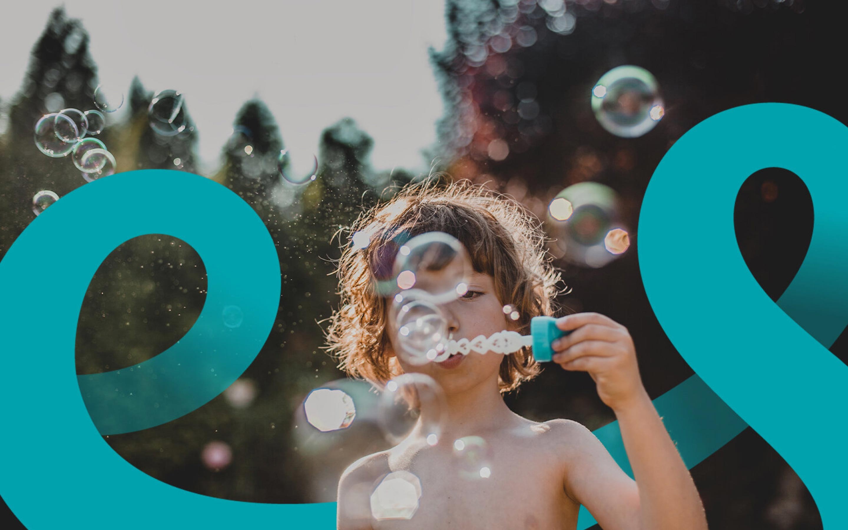 Teal letterform cropped over sunlit outdoor photography of a child and floating bubbles