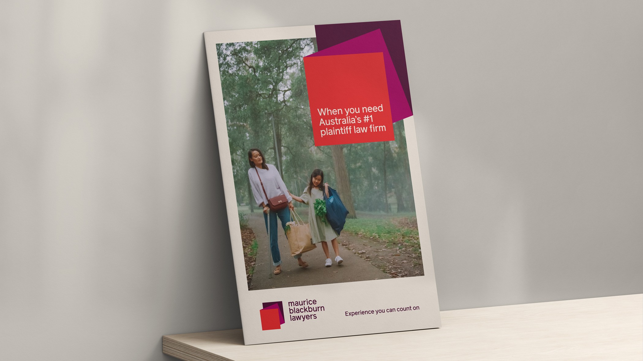 Brochure cover propped on a shelf, red headline panel over a photo of a woman and child walking
