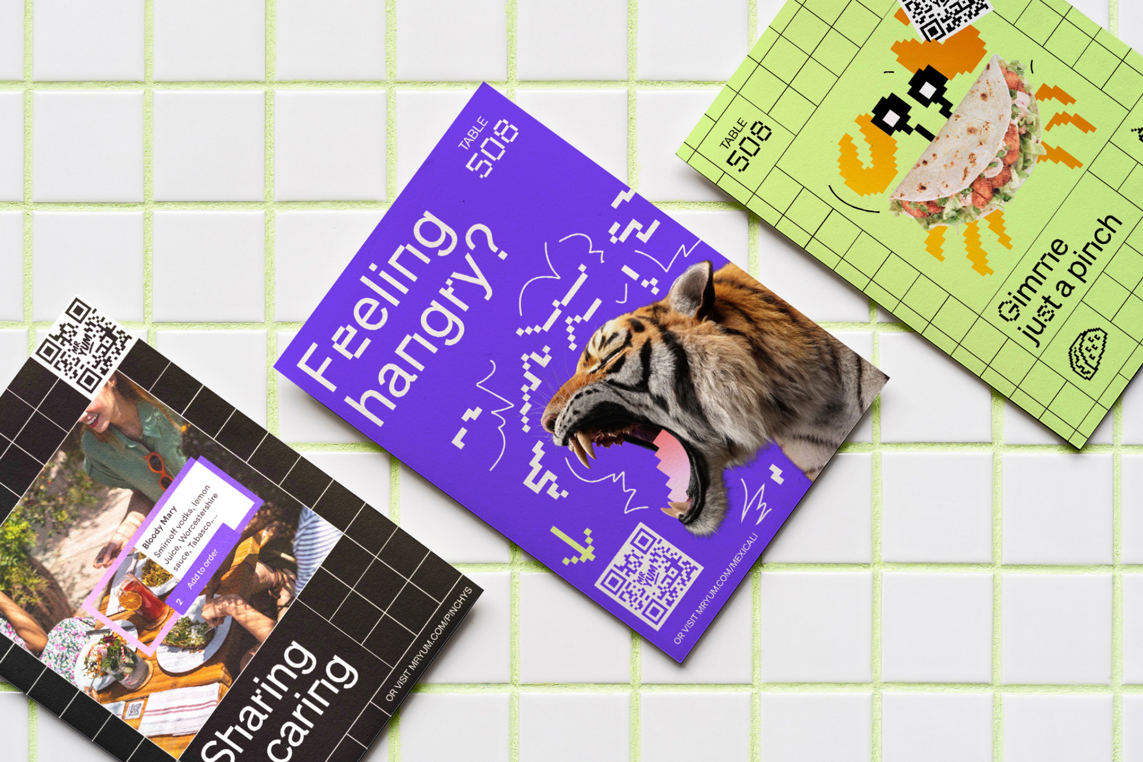 Mr Yum table cards fanned on tiles, including a 'Feeling hangry?' tiger card and a green taco card