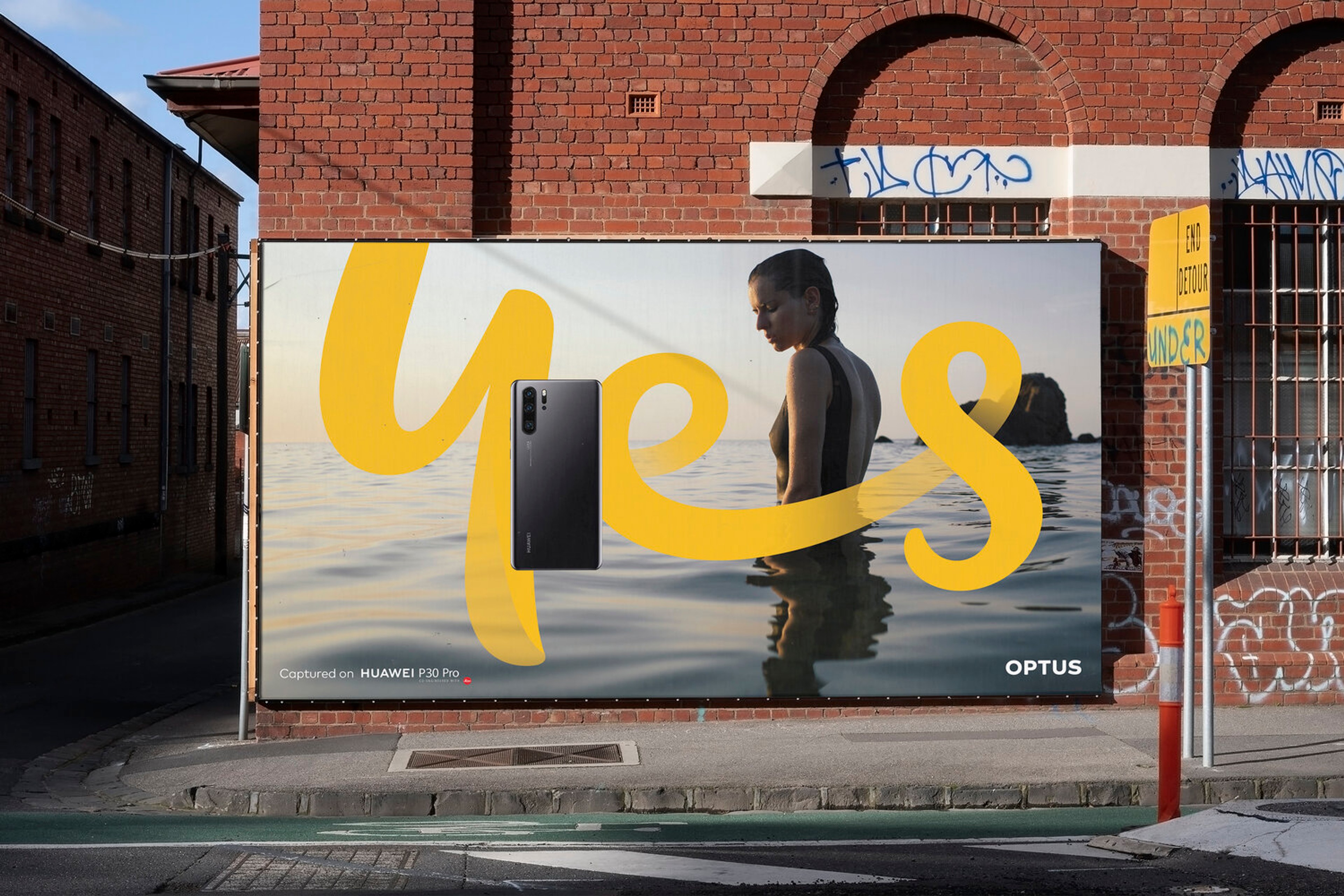 Street billboard with the yellow handwritten 'yes' script sweeping across an ocean photograph