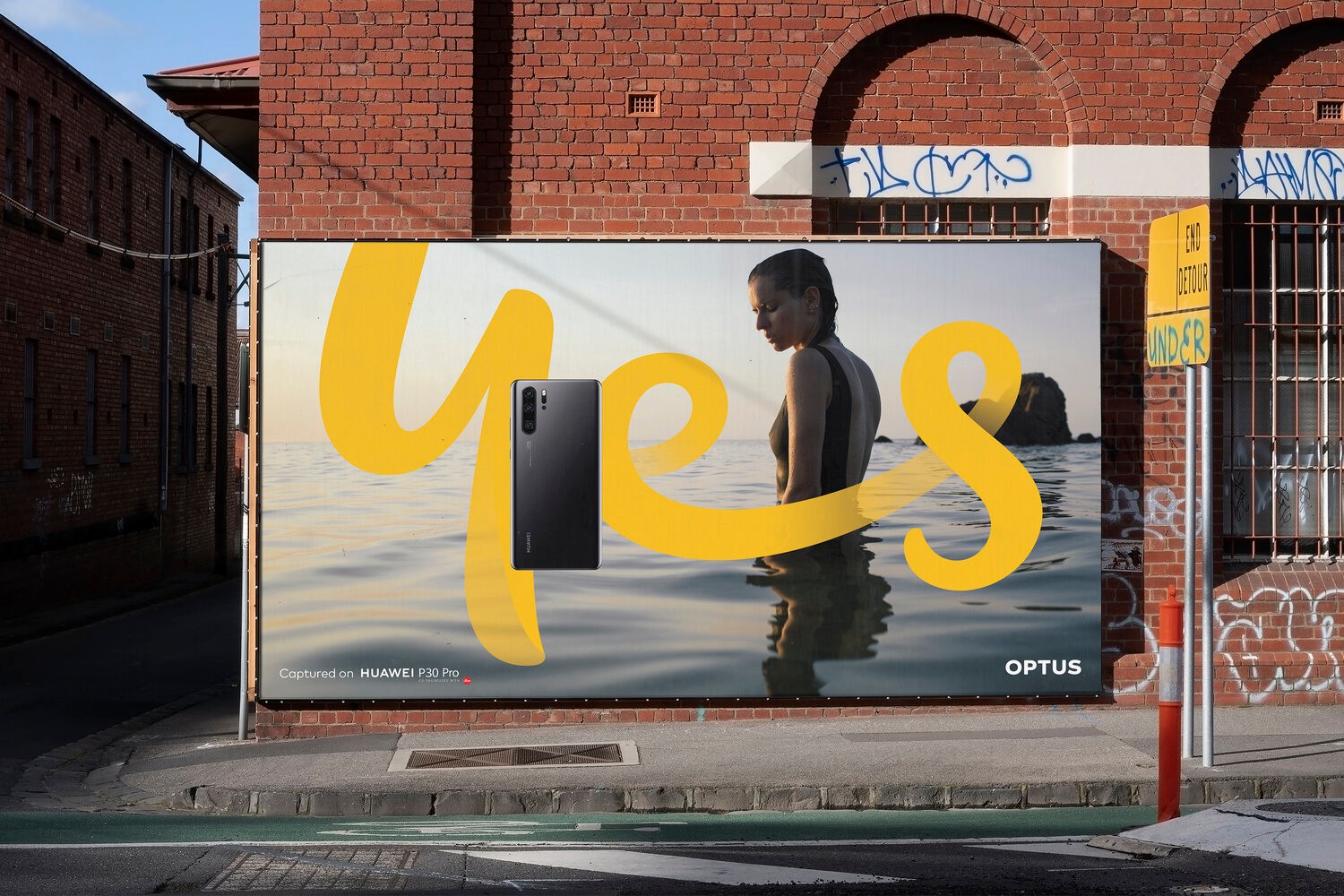 Street billboard with the yellow handwritten 'yes' script sweeping across an ocean photograph