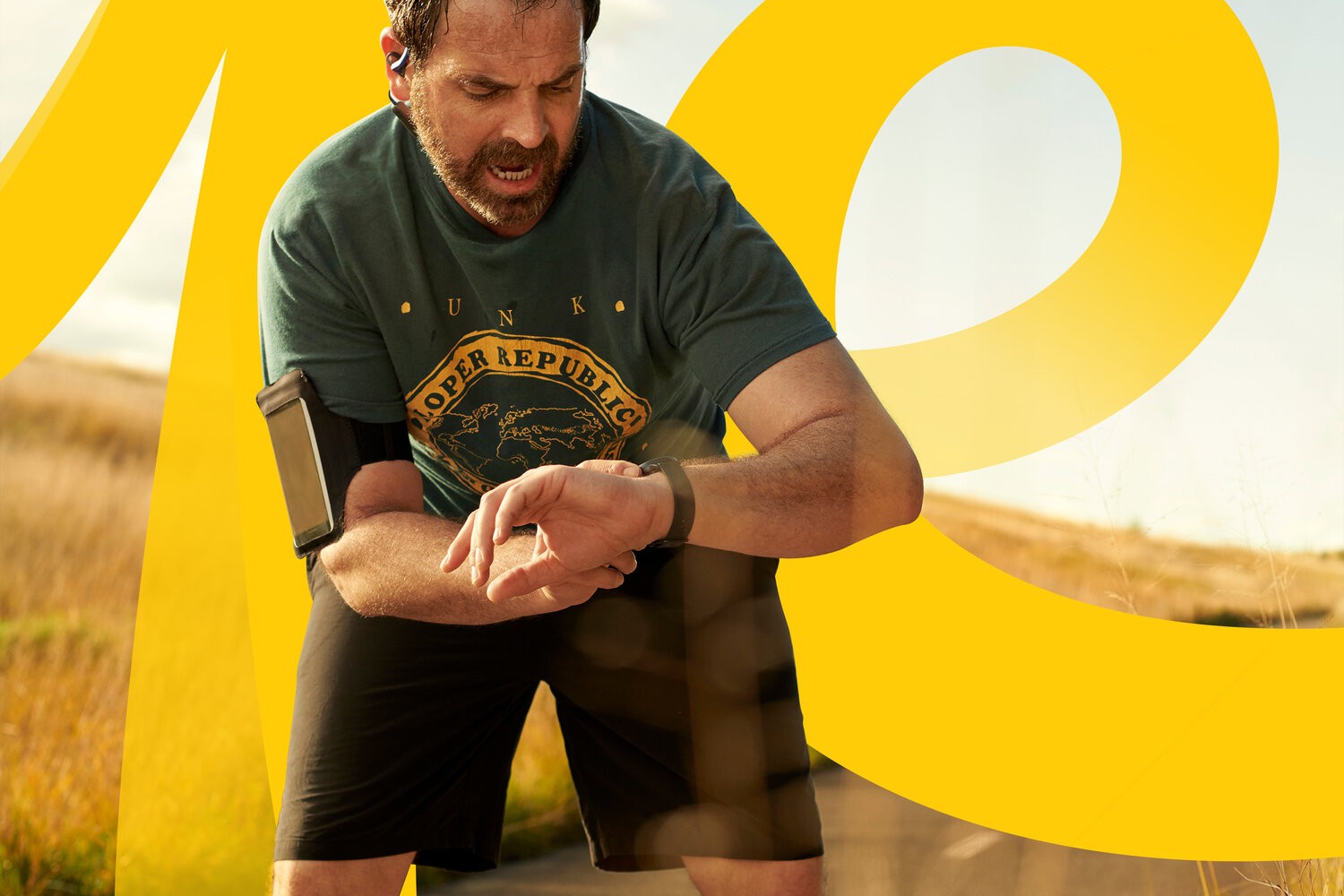 Runner checking a smartwatch behind translucent yellow letterforms from the 'yes' script