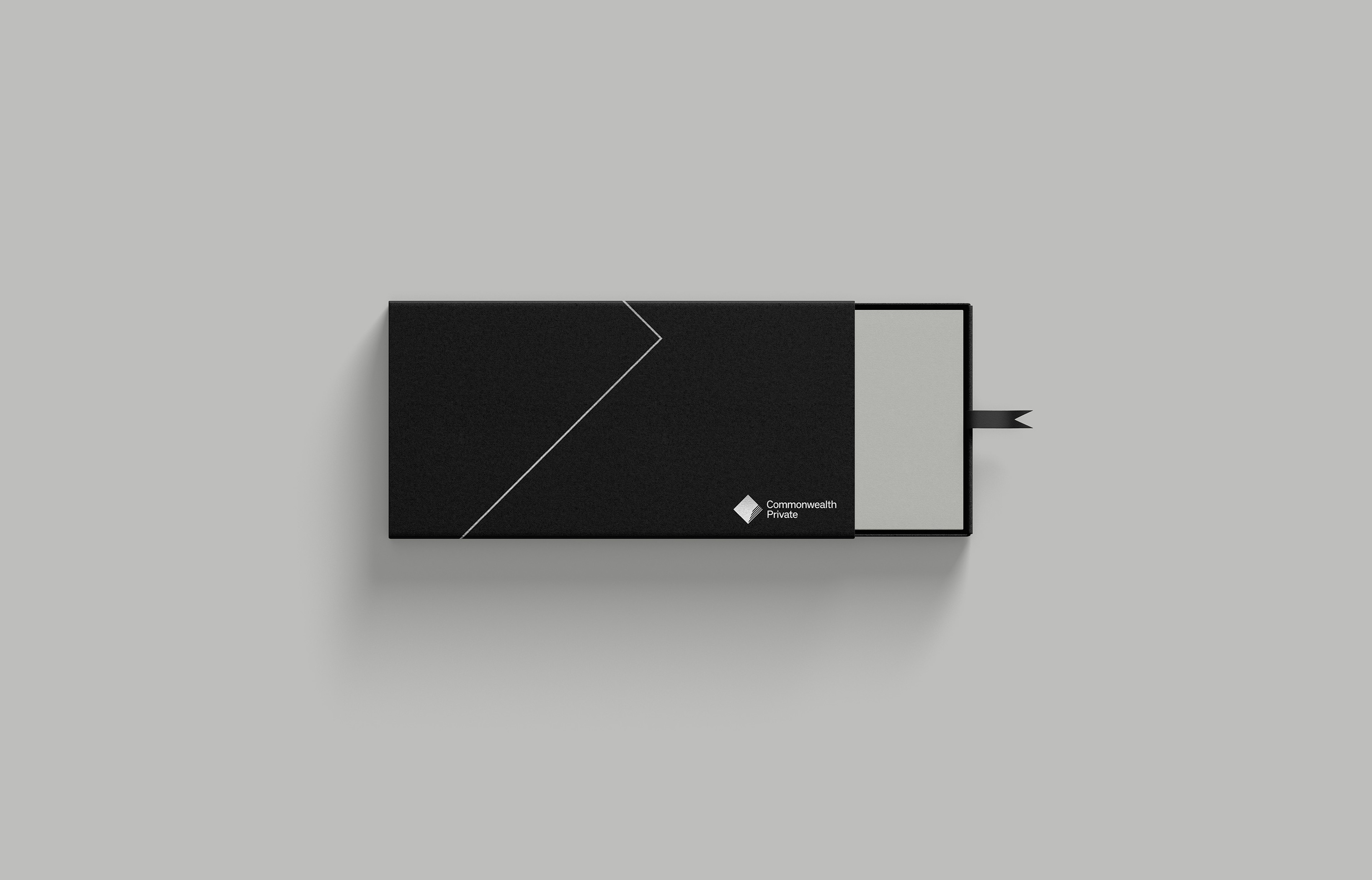 Black slipcase box with a silver chevron rule and the Commonwealth Private diamond mark