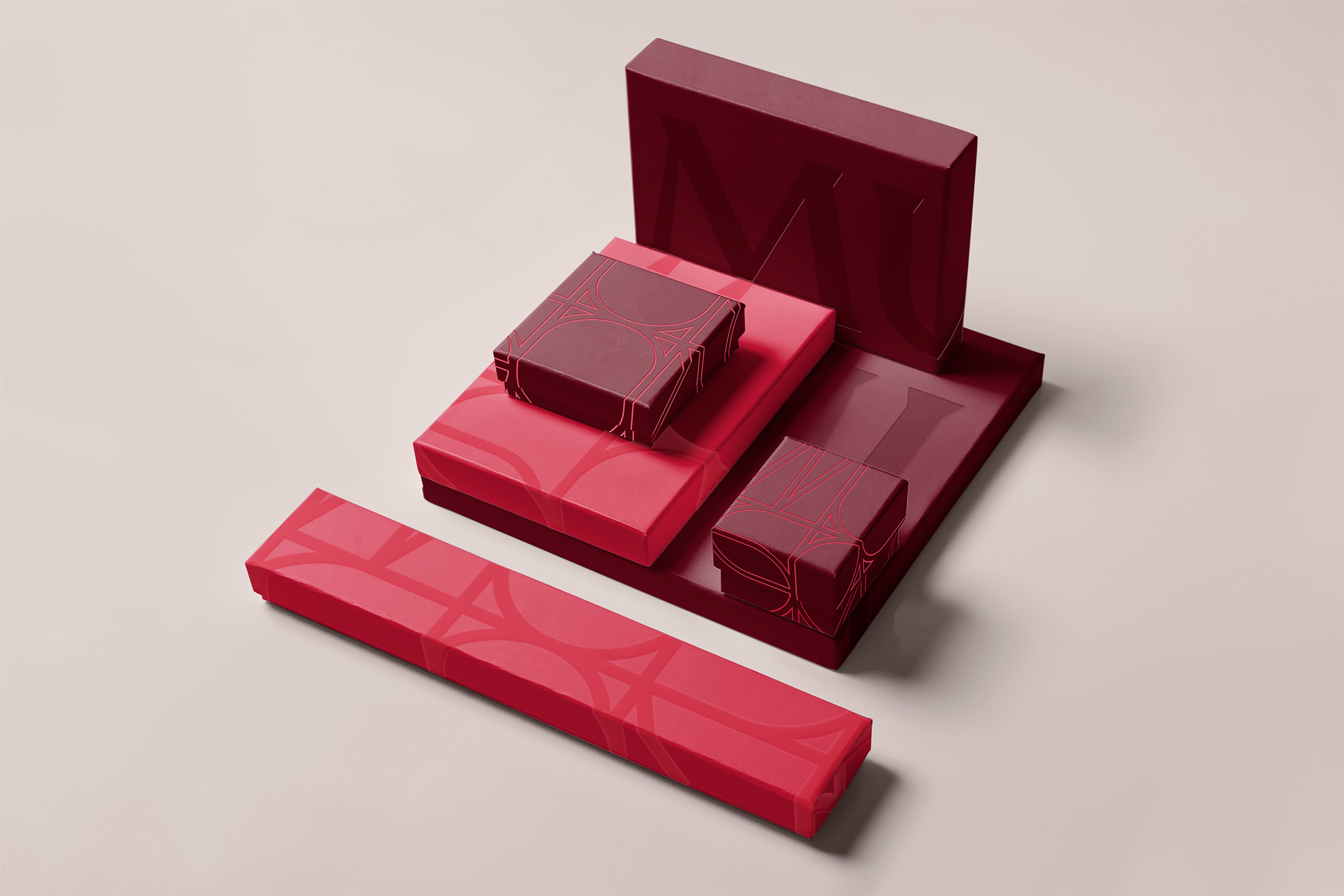 Nested gift boxes in raspberry and burgundy, embossed with oversized outlined letterforms