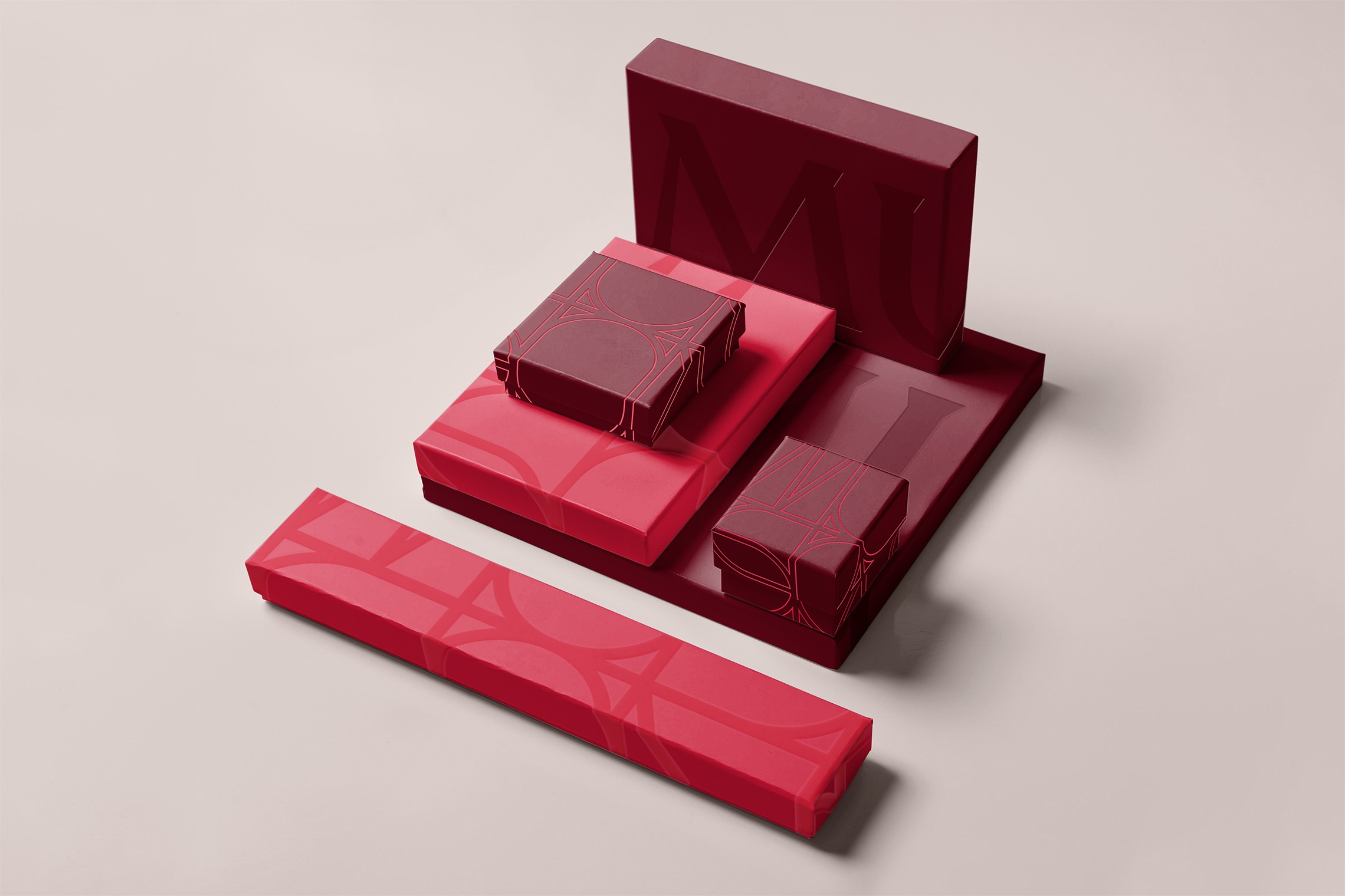 Nested gift boxes in raspberry and burgundy, embossed with oversized outlined letterforms