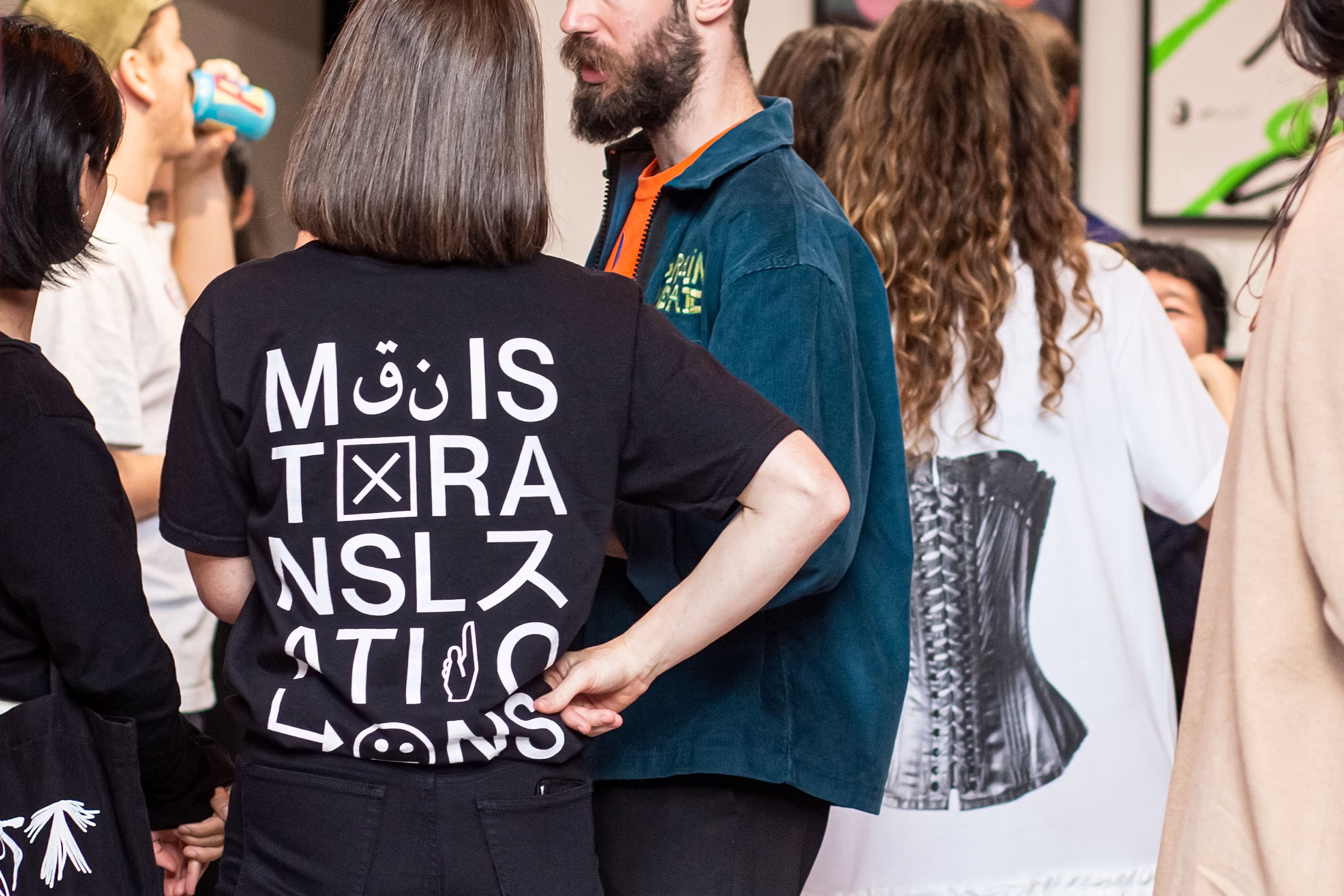 Guests at the Mistranslations opening, one wearing the black wordmark tee