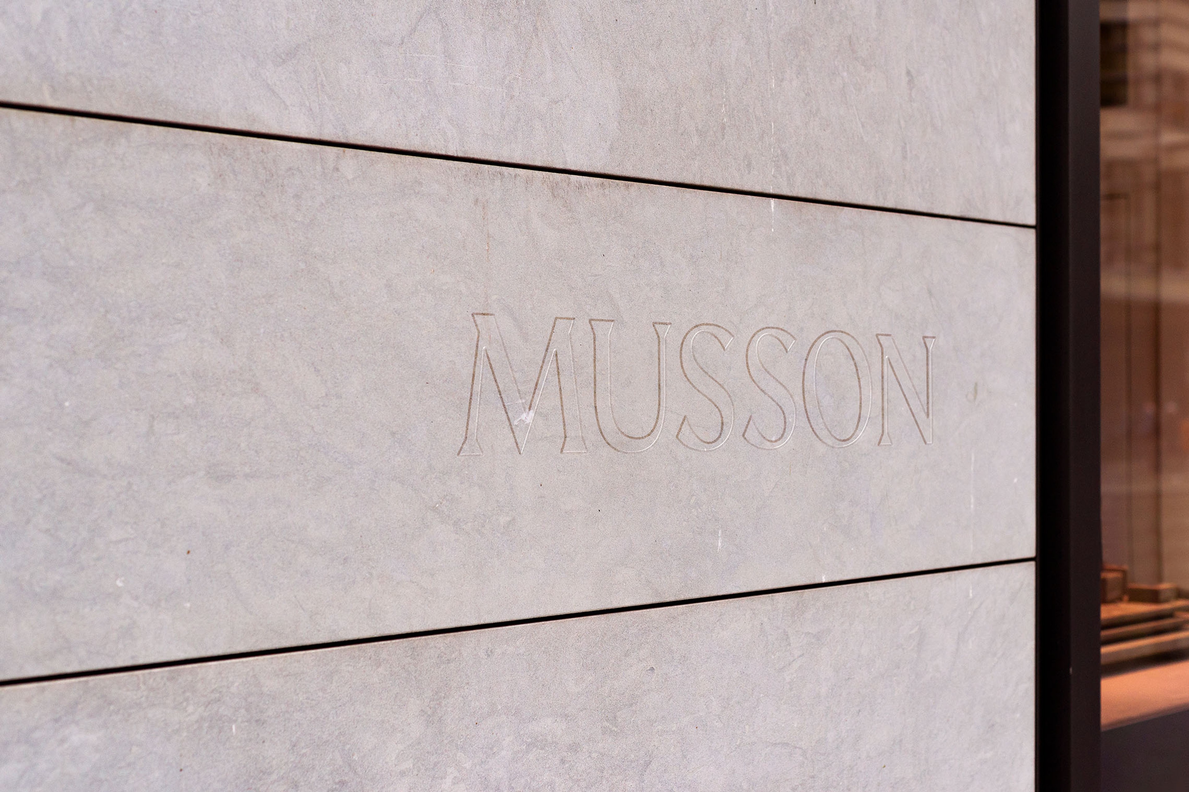 Boutique name engraved in fine outline lettering into the pale stone of the shopfront
