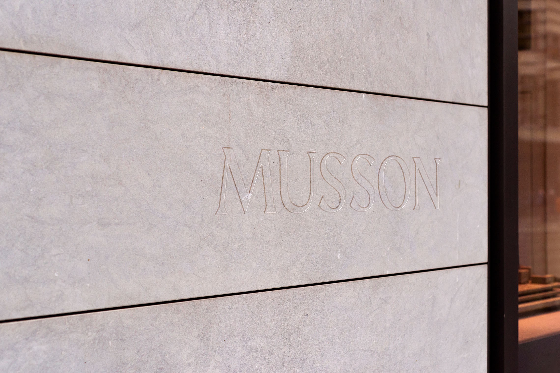 Boutique name engraved in fine outline lettering into the pale stone of the shopfront