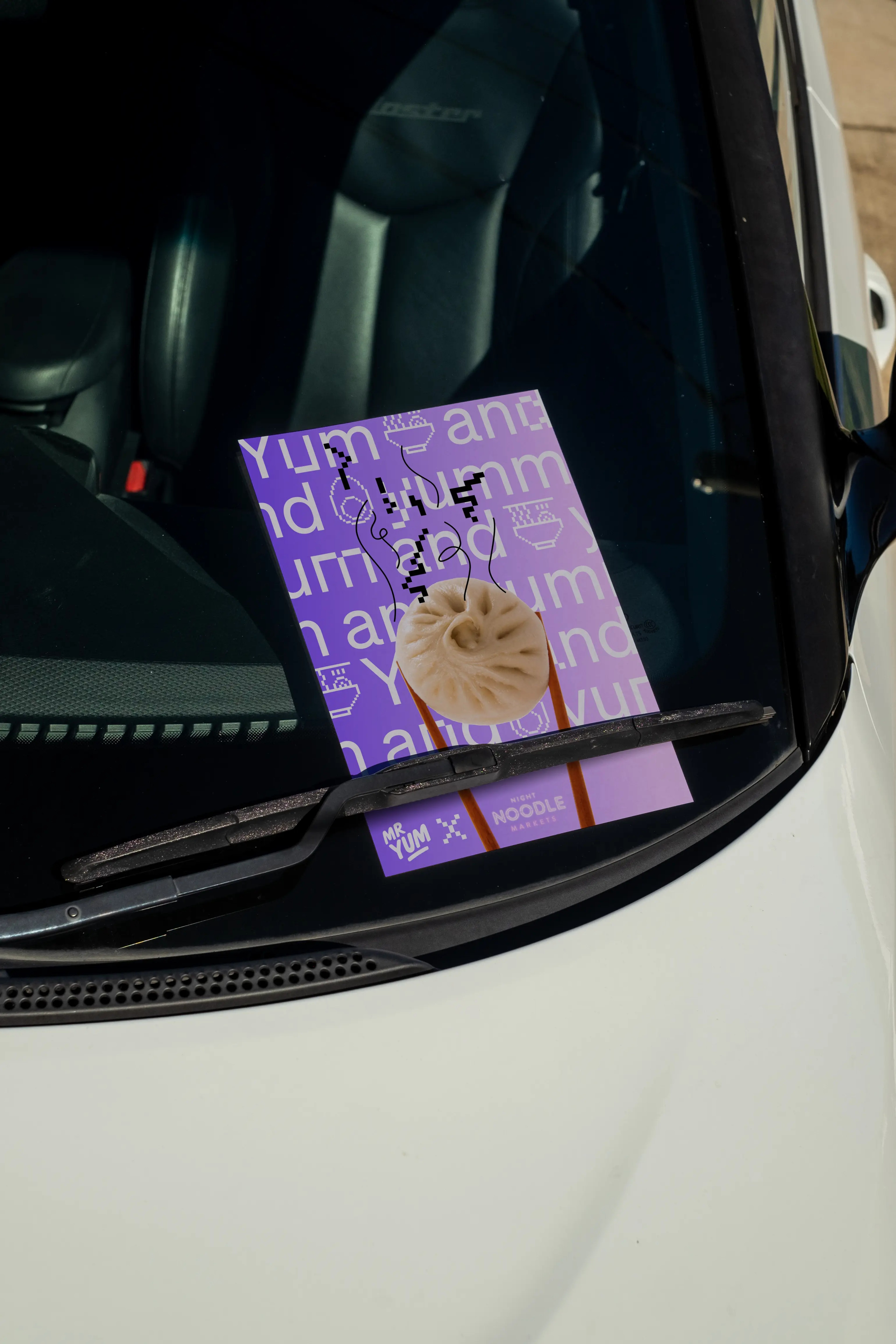 Purple Mr Yum x Noodle Markets flyer under a car wiper, steamed bun and chopstick artwork