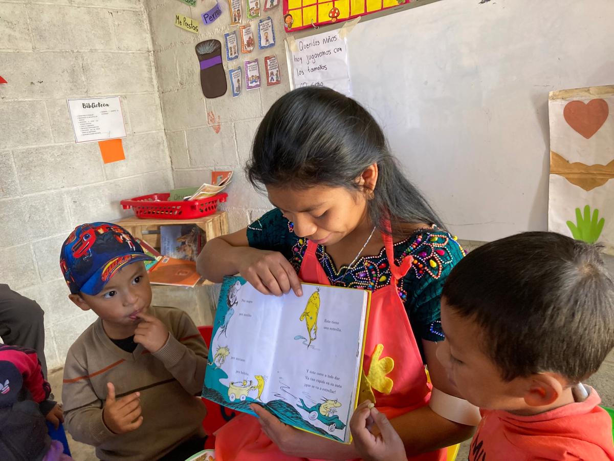 A Let's Be Ready teacher reading a picture book with two students